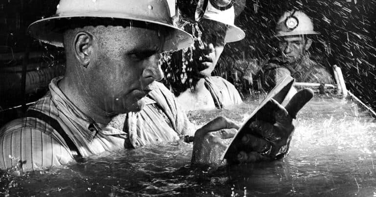 three people working in flooded pipe